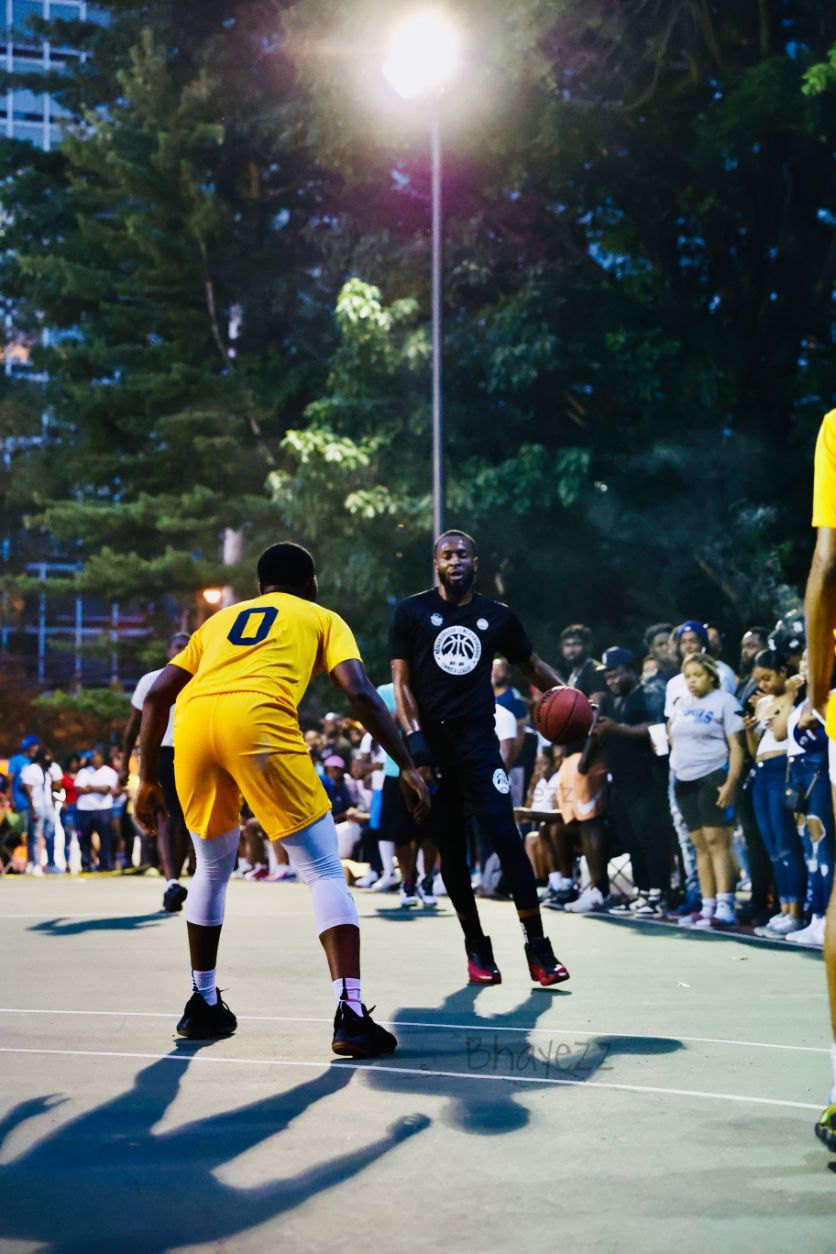 Basketball-games-with-crowd,-focus-on-two-black-male-basketball-players-1-in-yellow-basketball-uniform-other-in-black-basketball